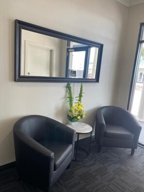 A room with two black armchairs, a small round table, and a mirror on the wall. - City West Motel (Mile End)