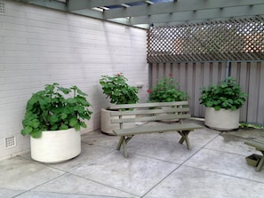 A patio area with a wooden bench, potted plants, and a wooden fence. - City West Motel (Mile End)