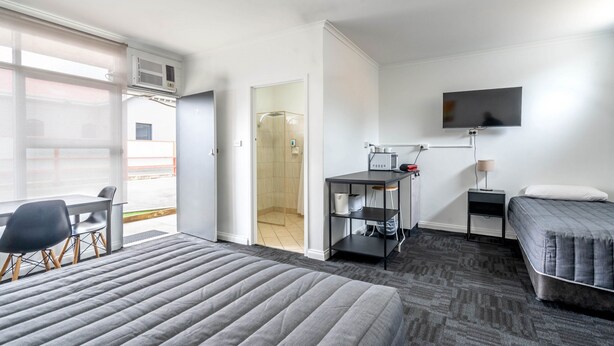 Hotelkamer met een bed, bureau, stoel, televisie en douchehoek.