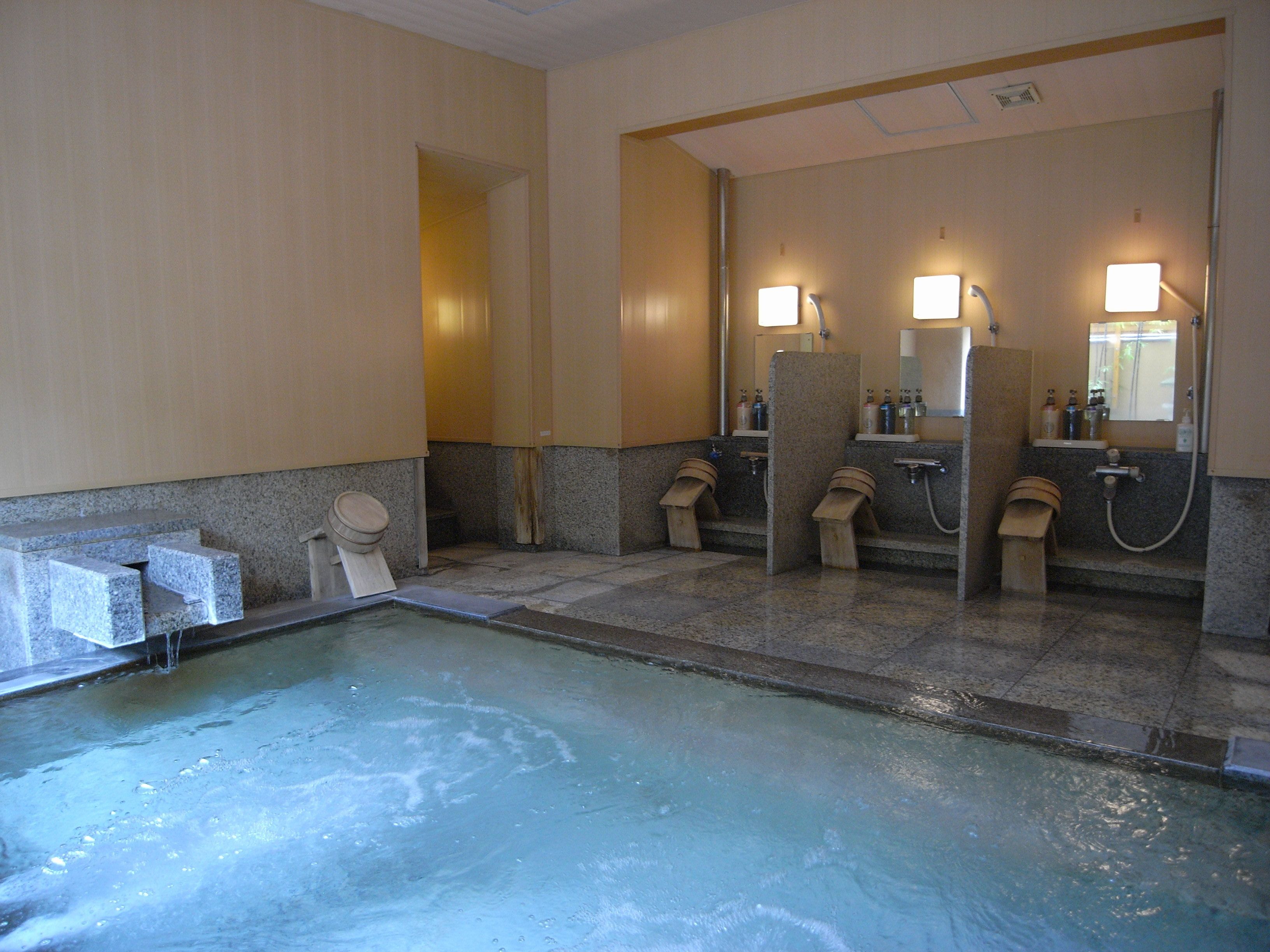 A public restroom with multiple sinks, mirrors, and a pool area.