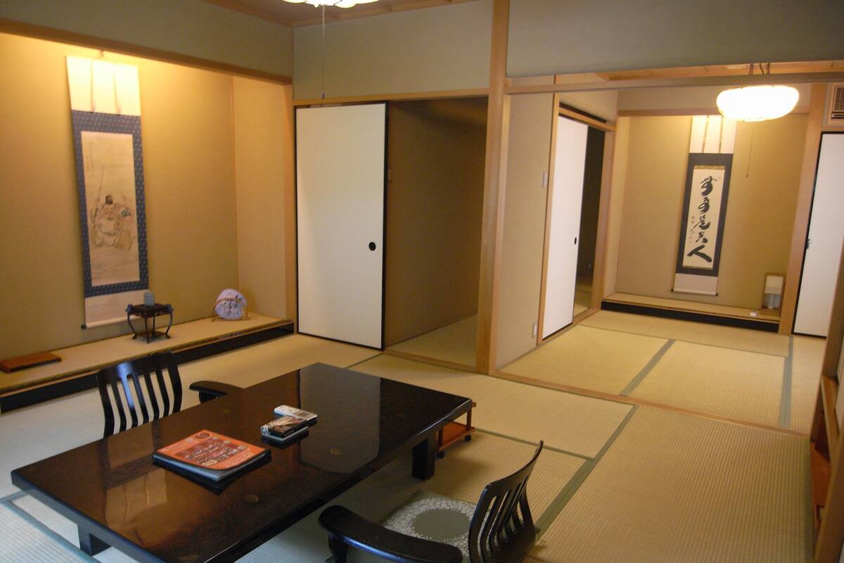 Ein traditioneller japanischer Raum mit Tatami-Böden, einem niedrigen Tisch mit Kissen und Schiebetüren.