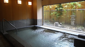 Baño de aguas termales con vista a un bosque de bambú.