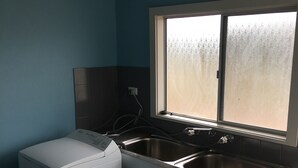 Una cocina compacta con lavadora, un lavamanos doble y un ventanal con vidrio esmerilado.