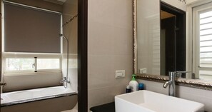 A bathroom with a bathtub, a shower, a sink, and a large mirror.