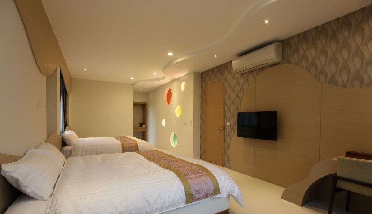 Een hotelkamer met twee bedden, een televisie en een klein bureau.