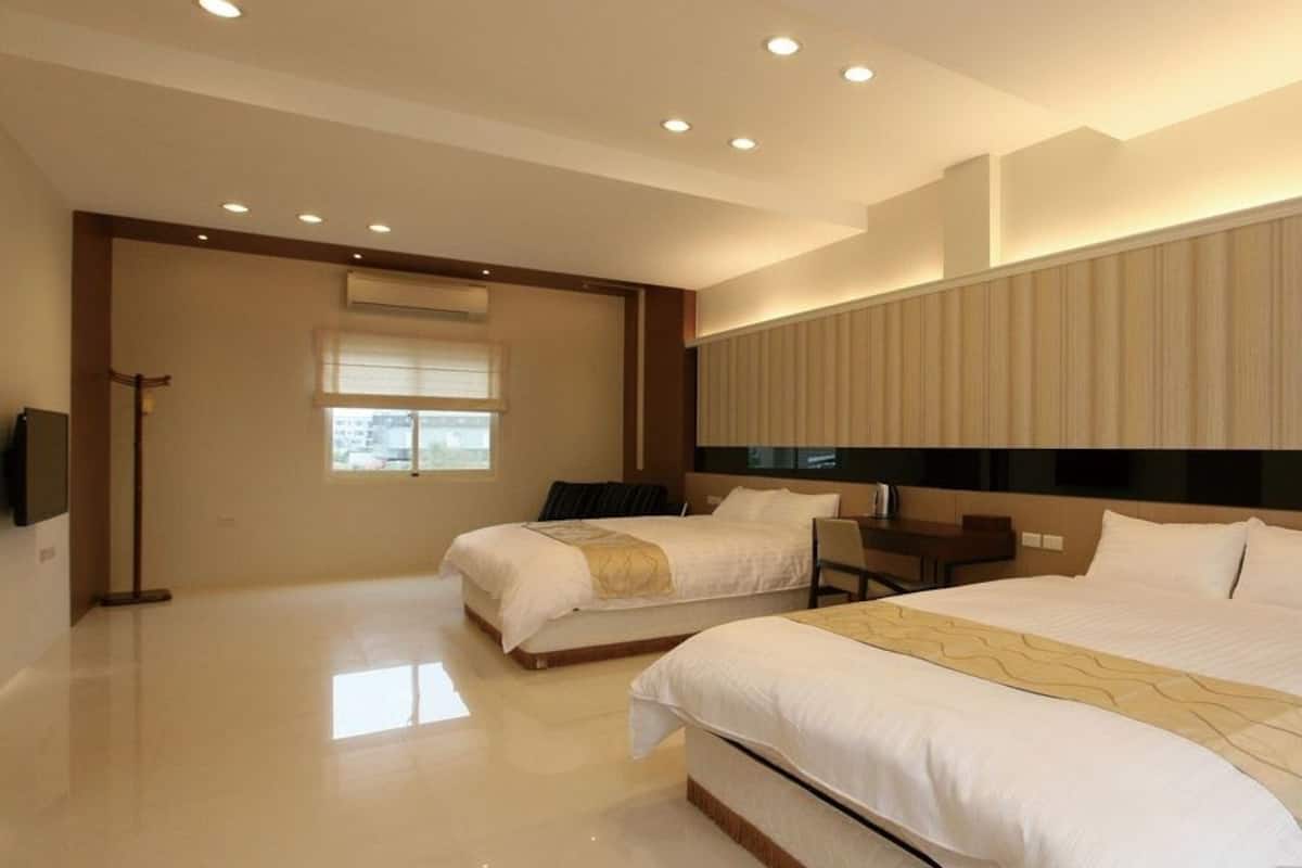 Quarto de hotel moderno com duas camas, uma escrivaninha e uma janela grande.