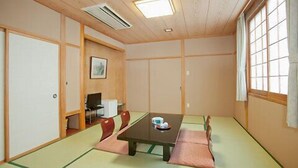 Una habitación japonesa tradicional con suelo de tatami, una mesa baja y un escritorio con una silla.