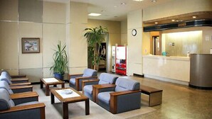 Un hall de hotel con zonas de estar, un mostrador de recepción y un reloj en la pared.