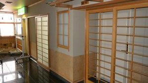 Un pasillo con puertas correderas, techo de madera y suelo de baldosas.