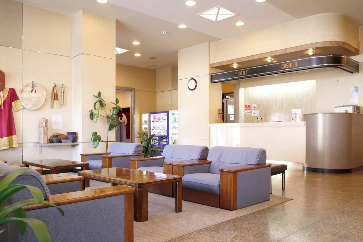 En hotellobby med sittgrupper, en receptionsdisk och en klocka på väggen.