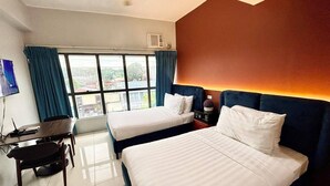 Habitación de hotel con dos camas, un escritorio con silla, un televisor y una ventana con cortinas.