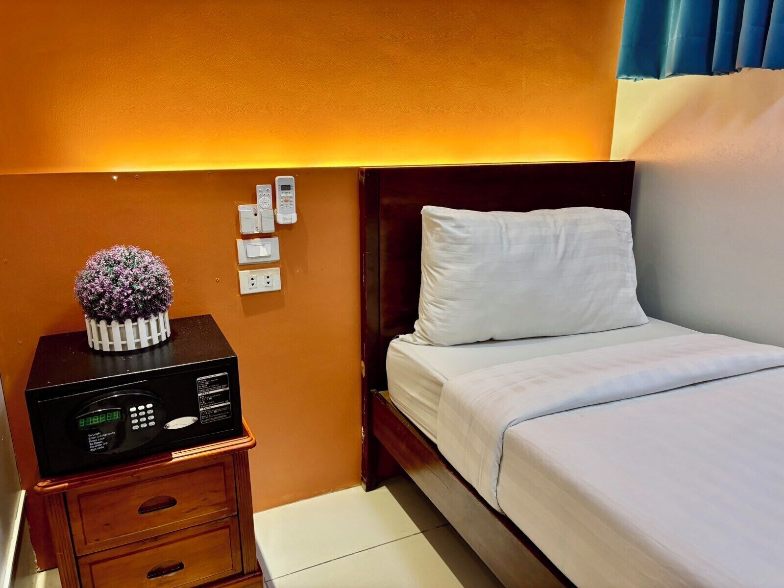 A hotel room with a bed, bedside table, and a digital clock.