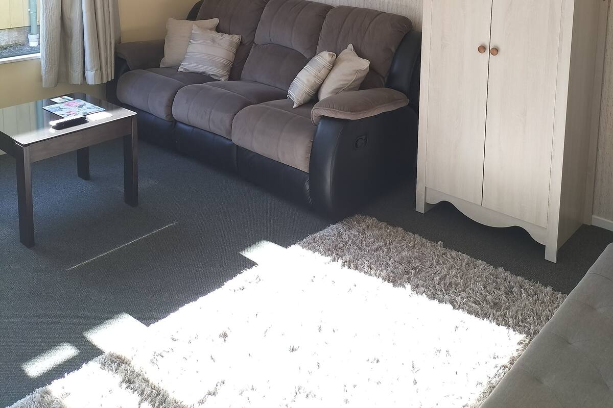 Una sala de estar con un sofá, una mesa de centro, un aparador y un cuadro en la pared.