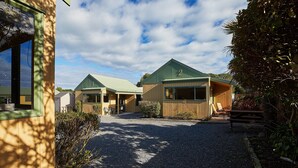 A building with a gravel driveway and a covered outdoor seating area. - Bay Cottages (Kaikoura)