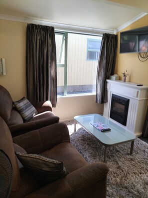 Stuga Comfort - 2 enkelsängar - tillgänglighetsanpassat - utsikt mot bergen (Adult Only) | Vardagsrum | 32-tums LED-tv med digitalkanaler, tv och eldstad