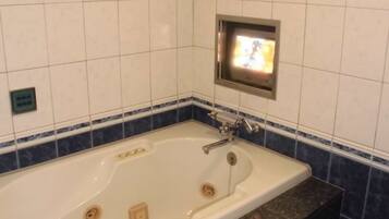 A bathroom with a bathtub, a mirror, and a sink.