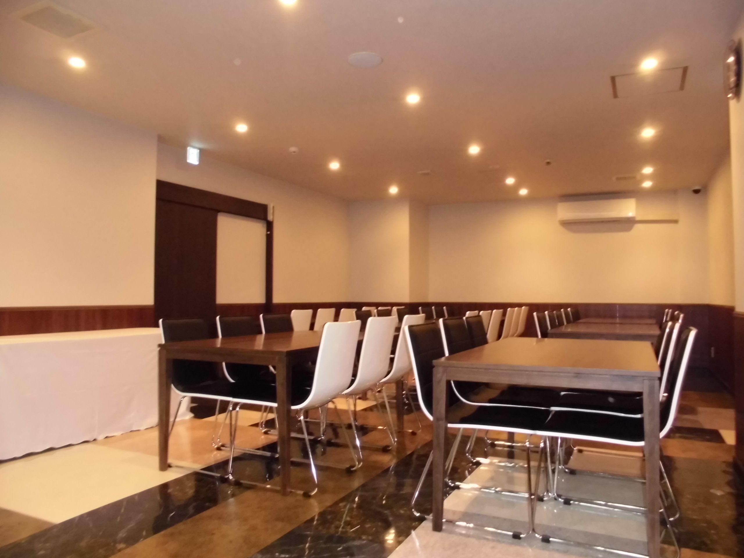 Un salón de conferencias con una larga mesa y sillas, equipado con luces en el techo y un equipo de aire acondicionado.