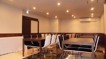 Un salón de conferencias con una larga mesa y sillas, equipado con luces en el techo y un equipo de aire acondicionado.