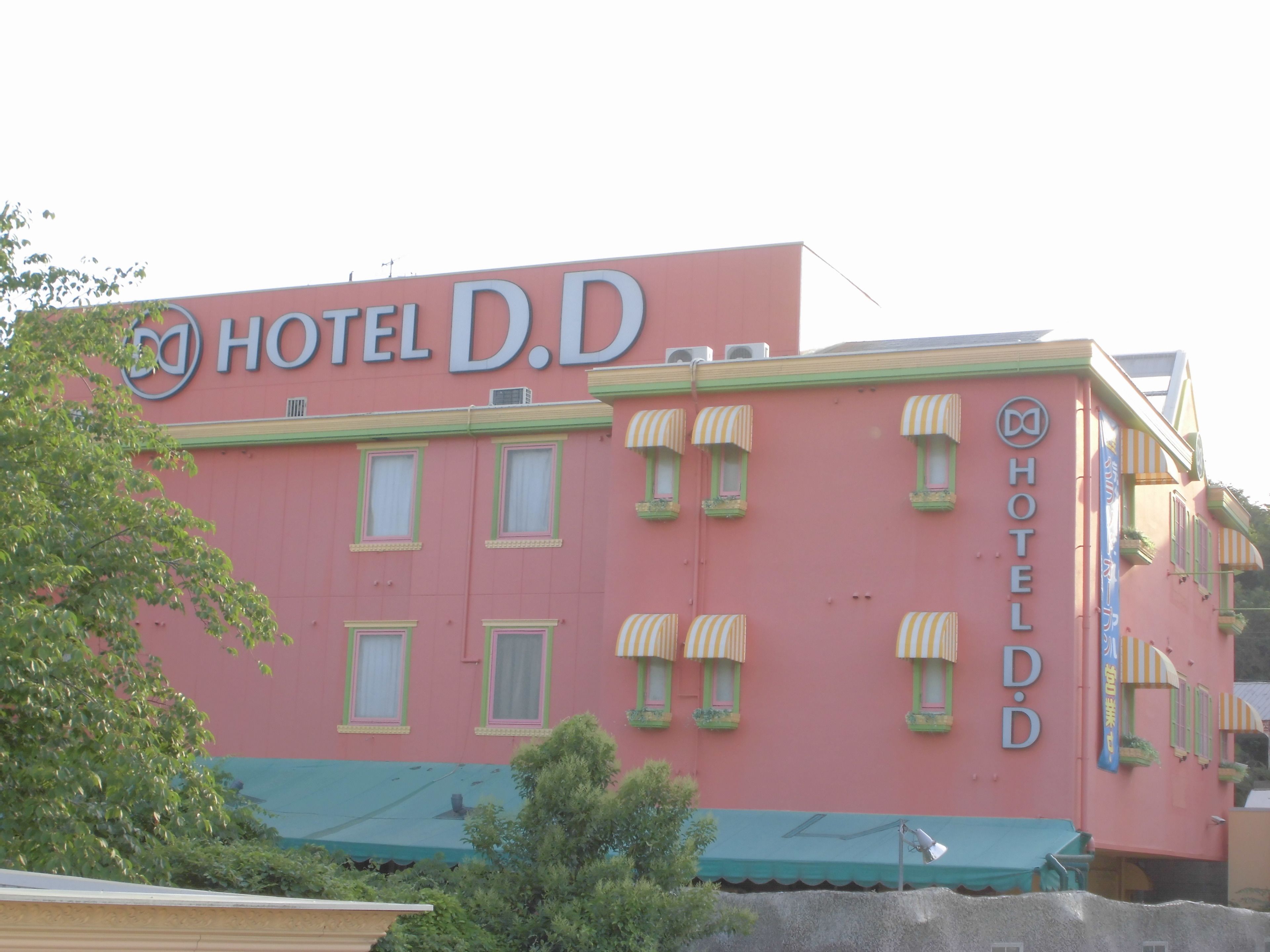 A pink building with the sign "HOTEL D.D." and multiple windows with striped awnings.