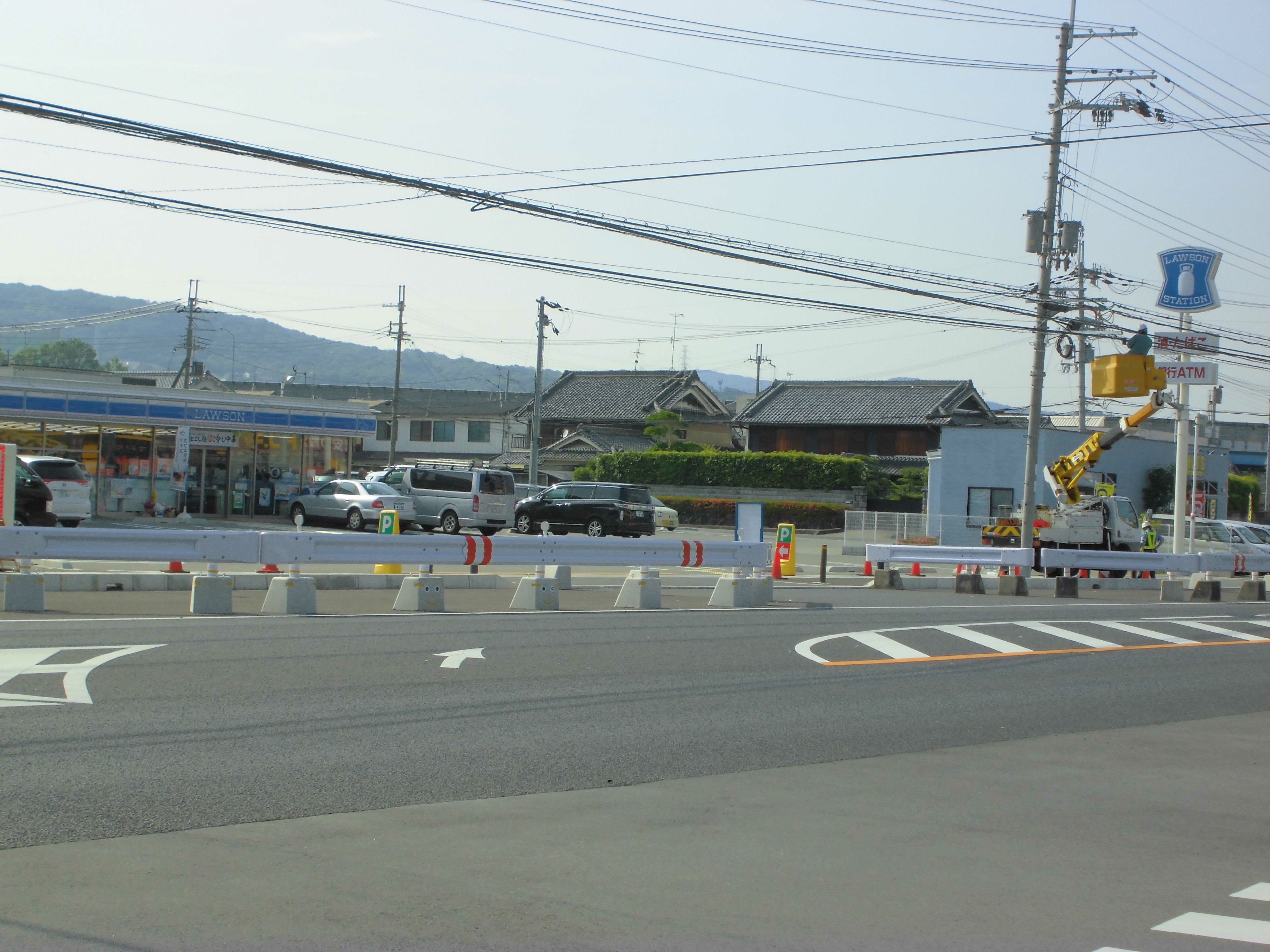 A street view with a Lawson station sign, vehicles, and a construction barrier.