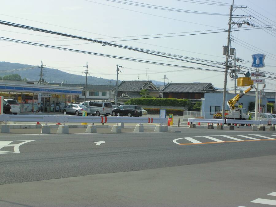 A street view with a Lawson station sign, vehicles, and a construction barrier.