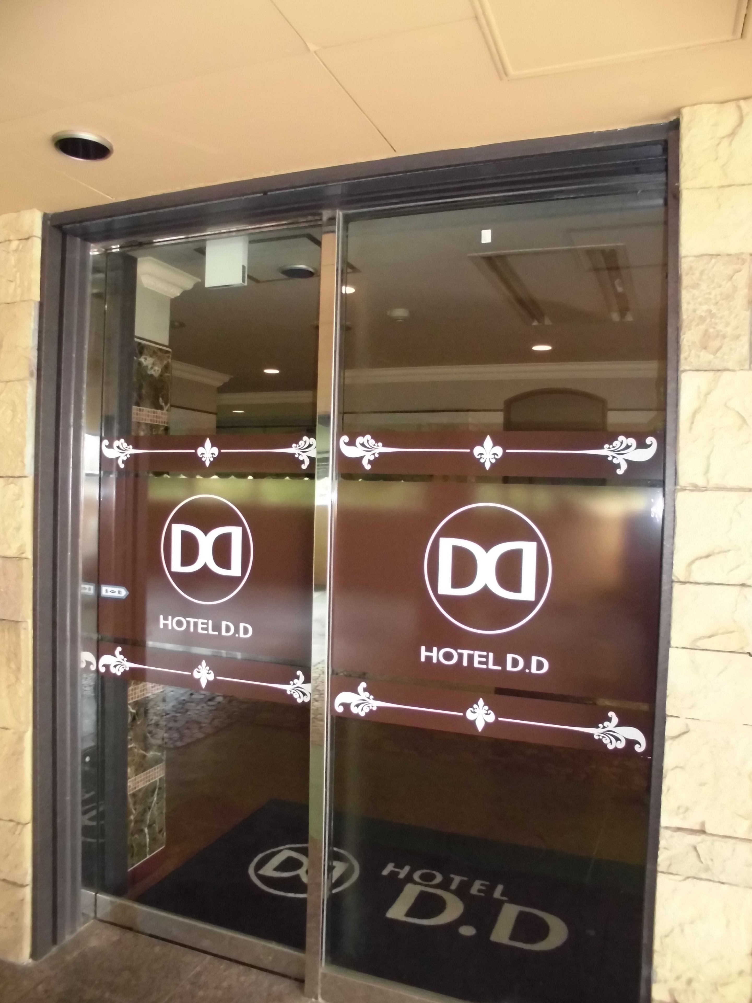 A hotel entrance with glass doors featuring the hotel's logo and name.