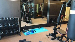 A gym with various exercise equipment, including dumbbells, a bench, and weight machines. - Qu Lin Resident (Sibu)