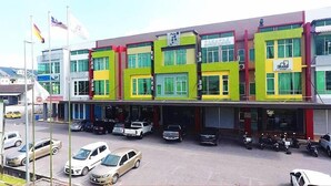 A multi-story building with a colorful facade, parked cars, and motorcycles in front. - Qu Lin Resident (Sibu)