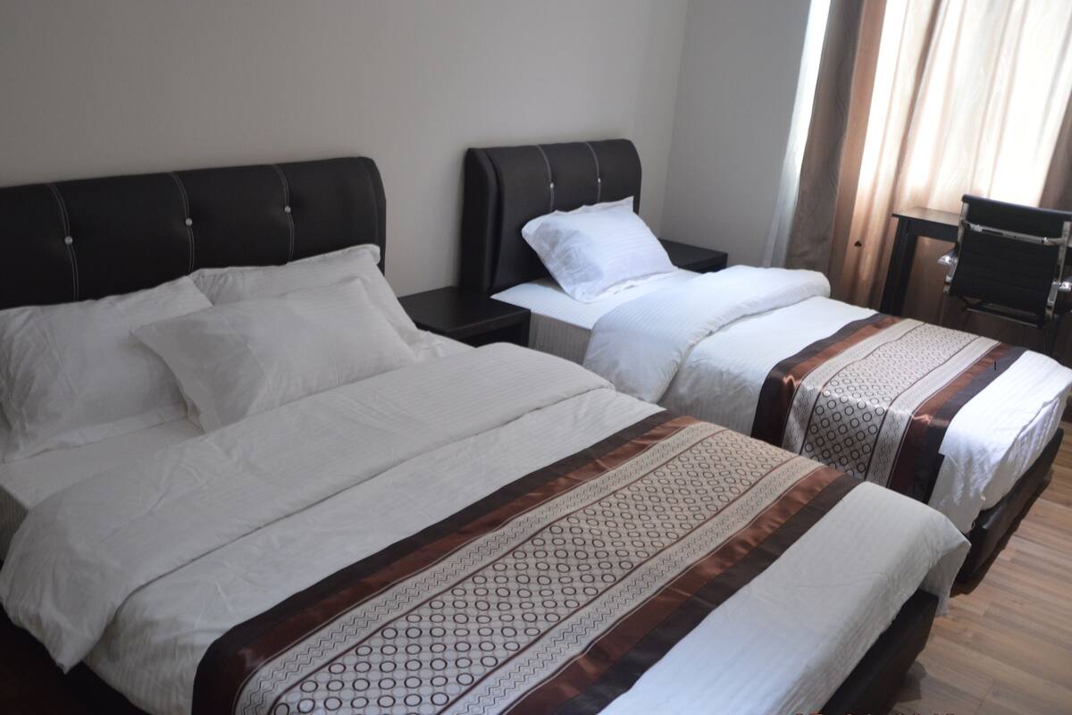 Quarto de hotel com duas camas, cada uma com cabeceira e mesas de cabeceira.