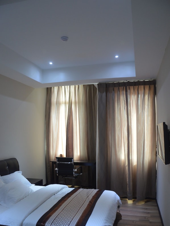 A hotel room with a bed, a desk, and curtains.