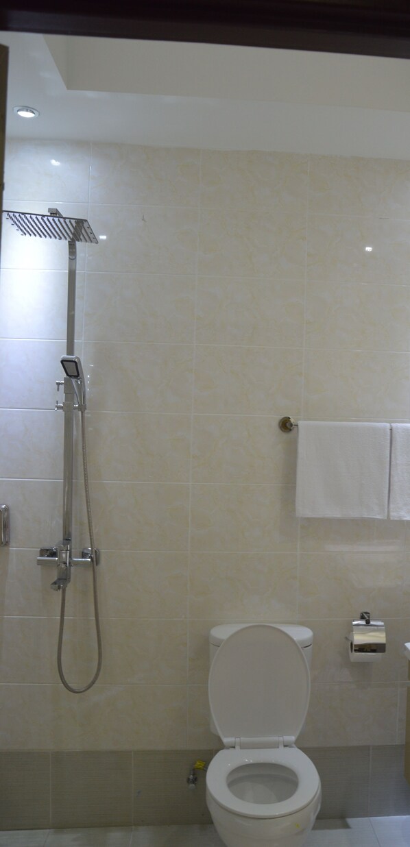 A bathroom with a shower, toilet, and a towel rack.