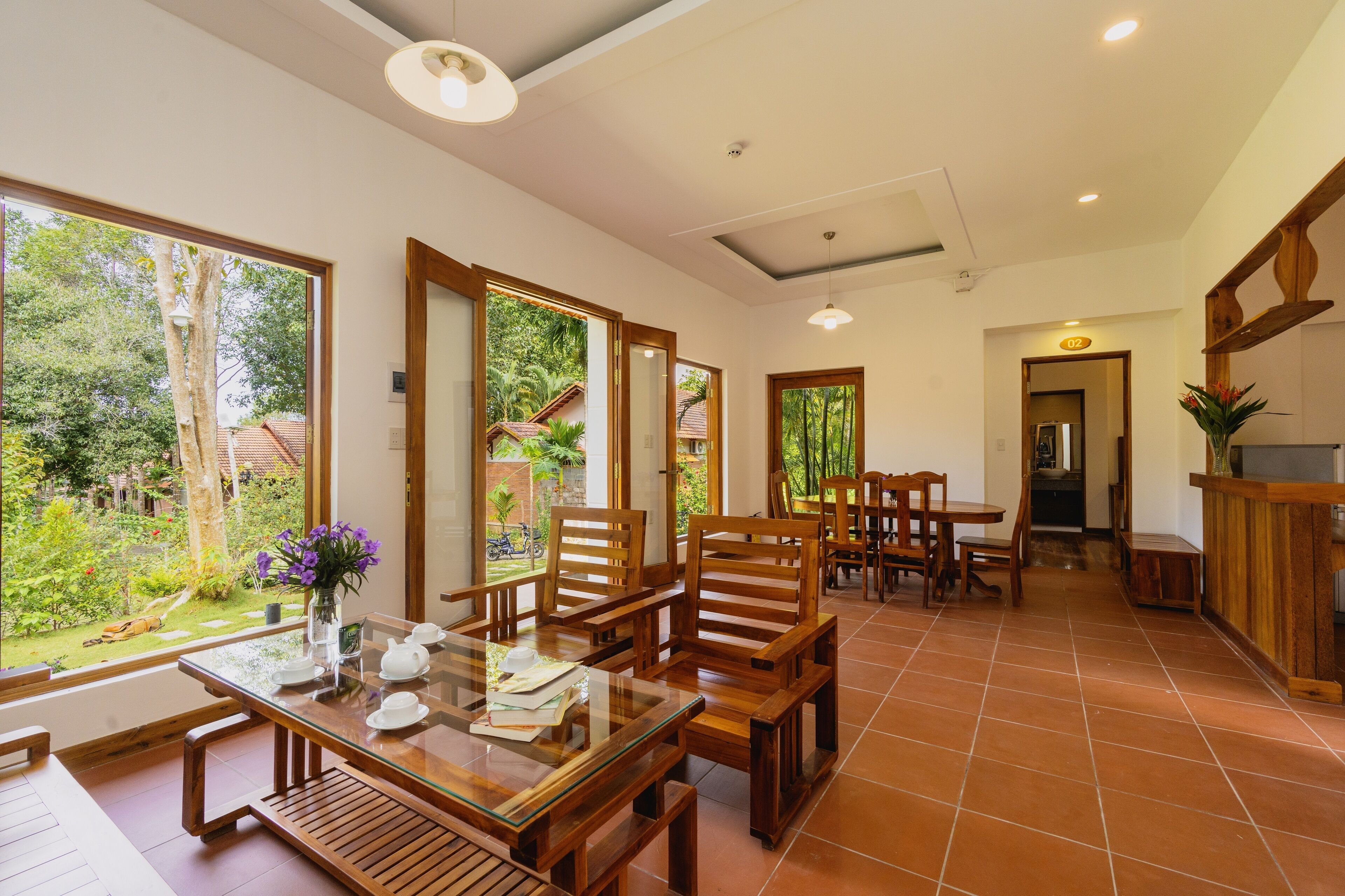 Una habitación amplia con zona de comedor, cocina y ventanas grandes que dan a un jardín.