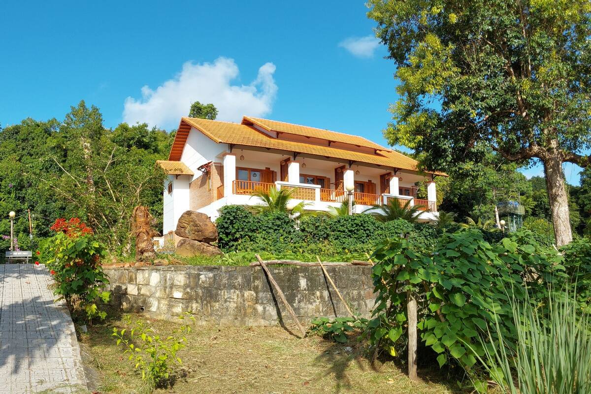 A two-story building with a stone staircase leading to a wooden deck.