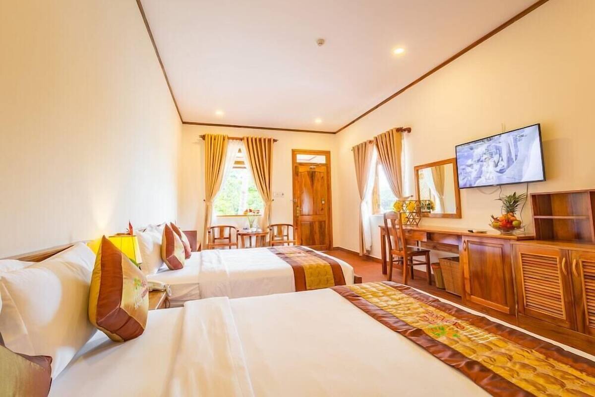 Une chambre d’hôtel avec deux lits, un bureau, une télévision et une vue sur l’extérieur.
