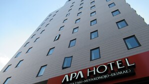 Un edificio de hotel con un cartel que dice "APA HOTEL" y "MIYAZAKI-MIYAKONOJO-EKIMAE".