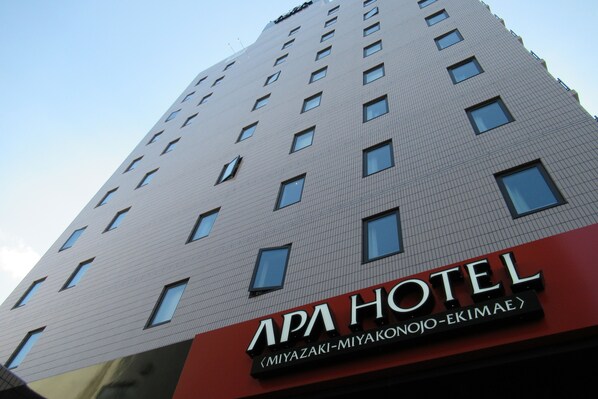 Un edificio de hotel con un cartel que dice "APA HOTEL" y "MIYAZAKI-MIYAKONOJO-EKIMAE".