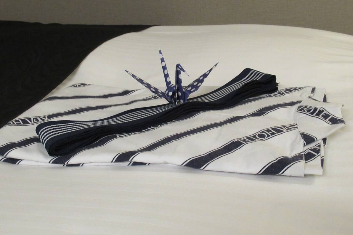 A neatly folded white and black striped shirt with a bow on a bed.