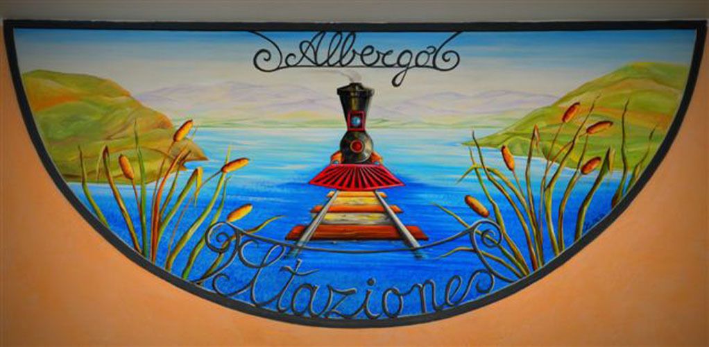 Un mural que muestra un tren, agua y el texto 'Albergas' y 'Estaciones'.