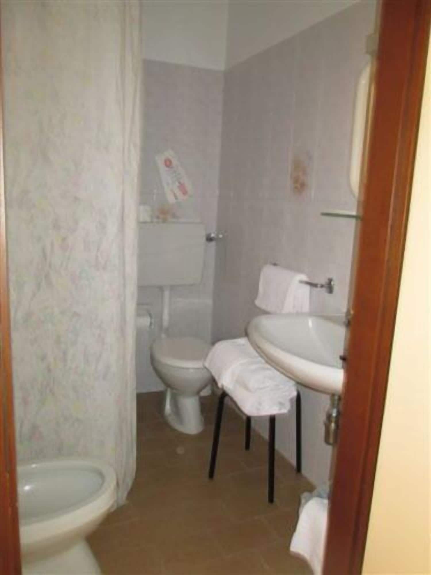 Un baño pequeño y sencillo con inodoro, lavamanos y cortina de ducha.