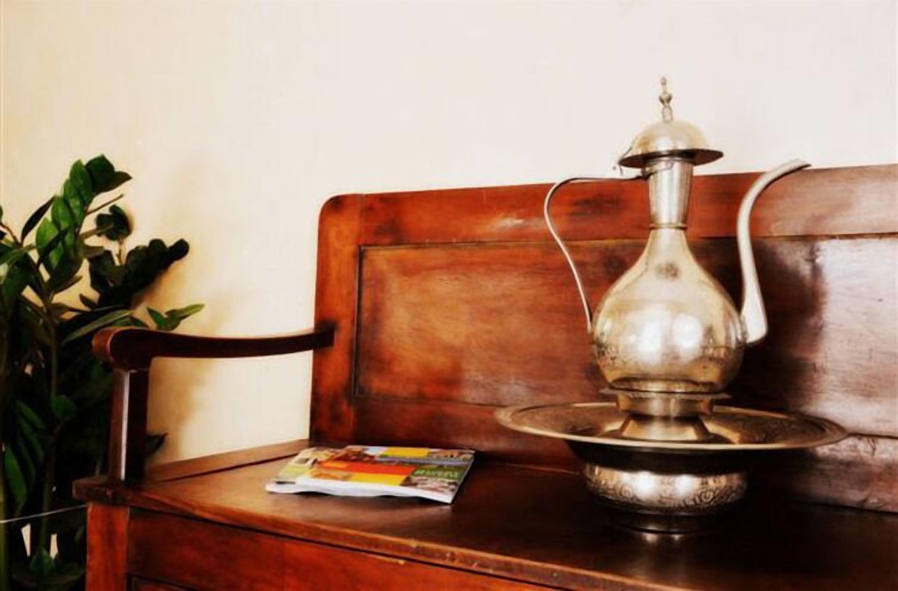 A wooden bench with a metal water dispenser and a magazine on it.