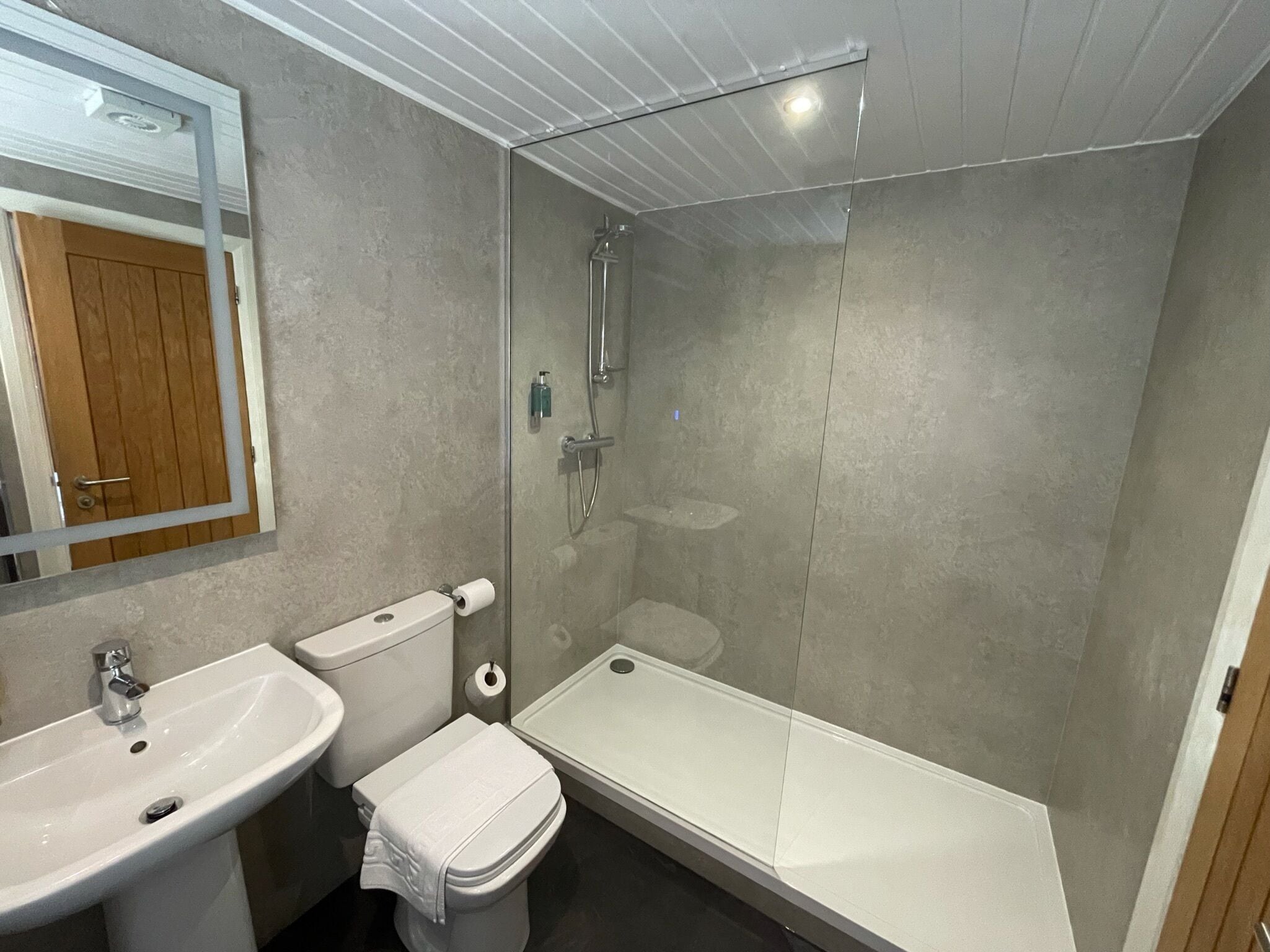A modern bathroom with a toilet, sink, and glass-enclosed shower.