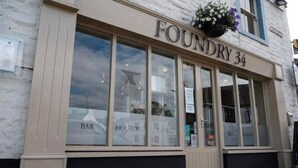 Un bâtiment sur lequel on peut lire l’inscription « FONDERIE 34 », avec de grandes fenêtres portant les mentions « BAR » et « BRASSERIES ».