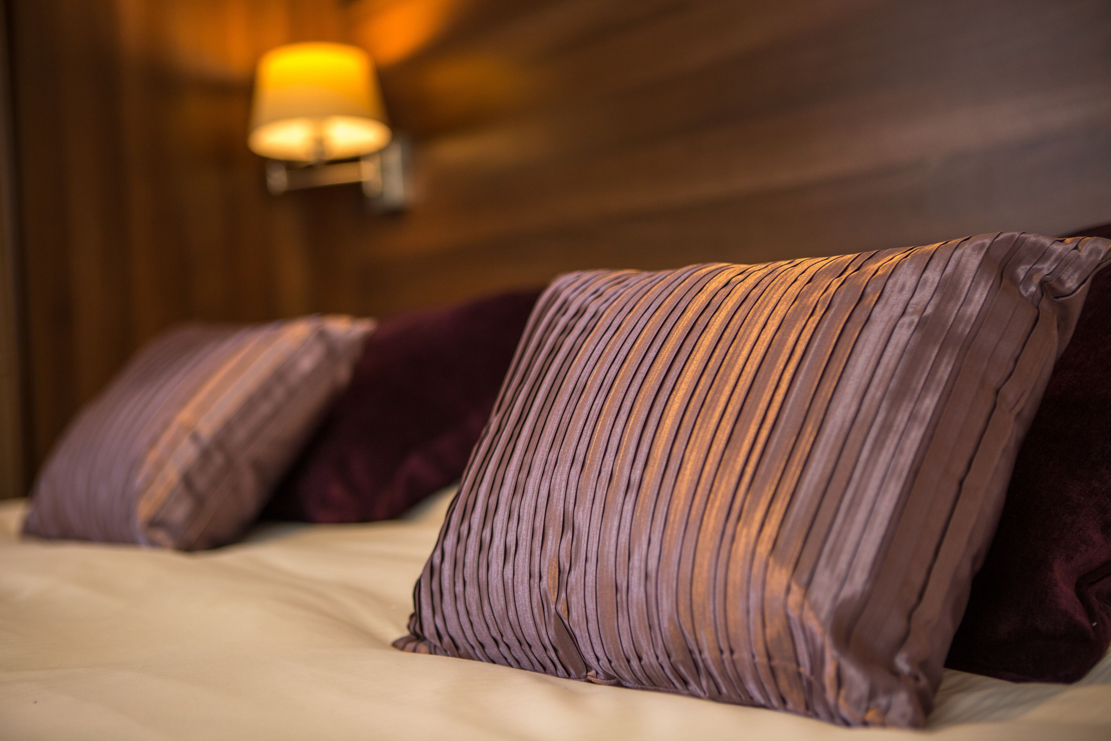 A bed with multiple pillows and a wall-mounted light fixture.
