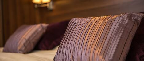 A bed with multiple pillows and a wall-mounted light fixture.