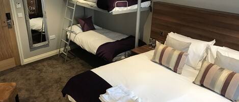 A hotel room with a bunk bed, a large mirror, a wooden headboard, and a carpeted floor.