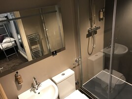 Un baño moderno con cabina de ducha de vidrio, lavamanos blanco y un inodoro.