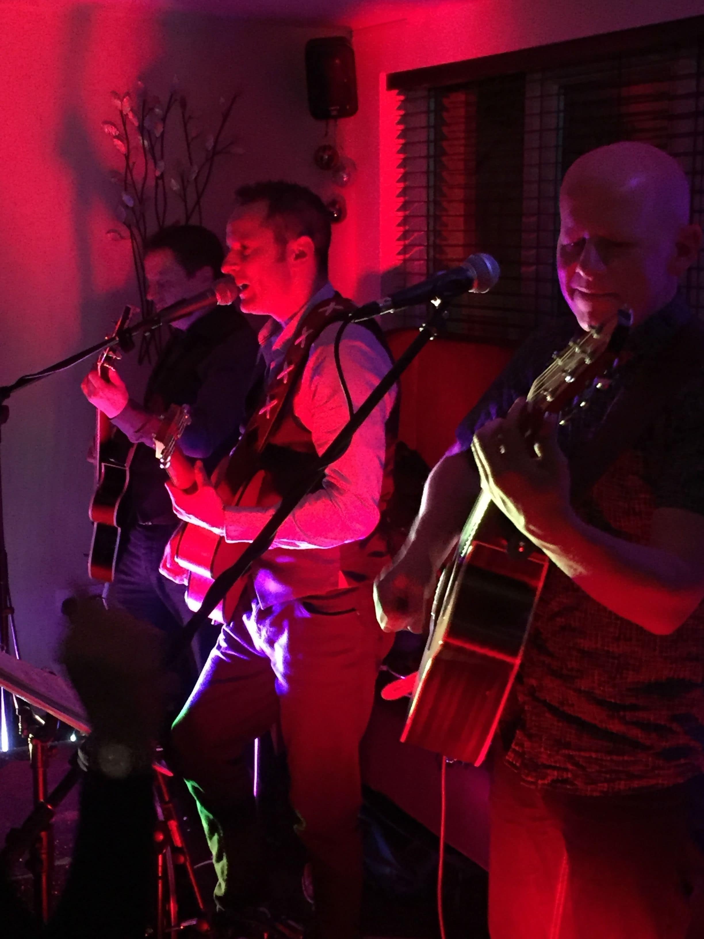 Una banda actuando en el escenario con instrumentos musicales y un micrófono.