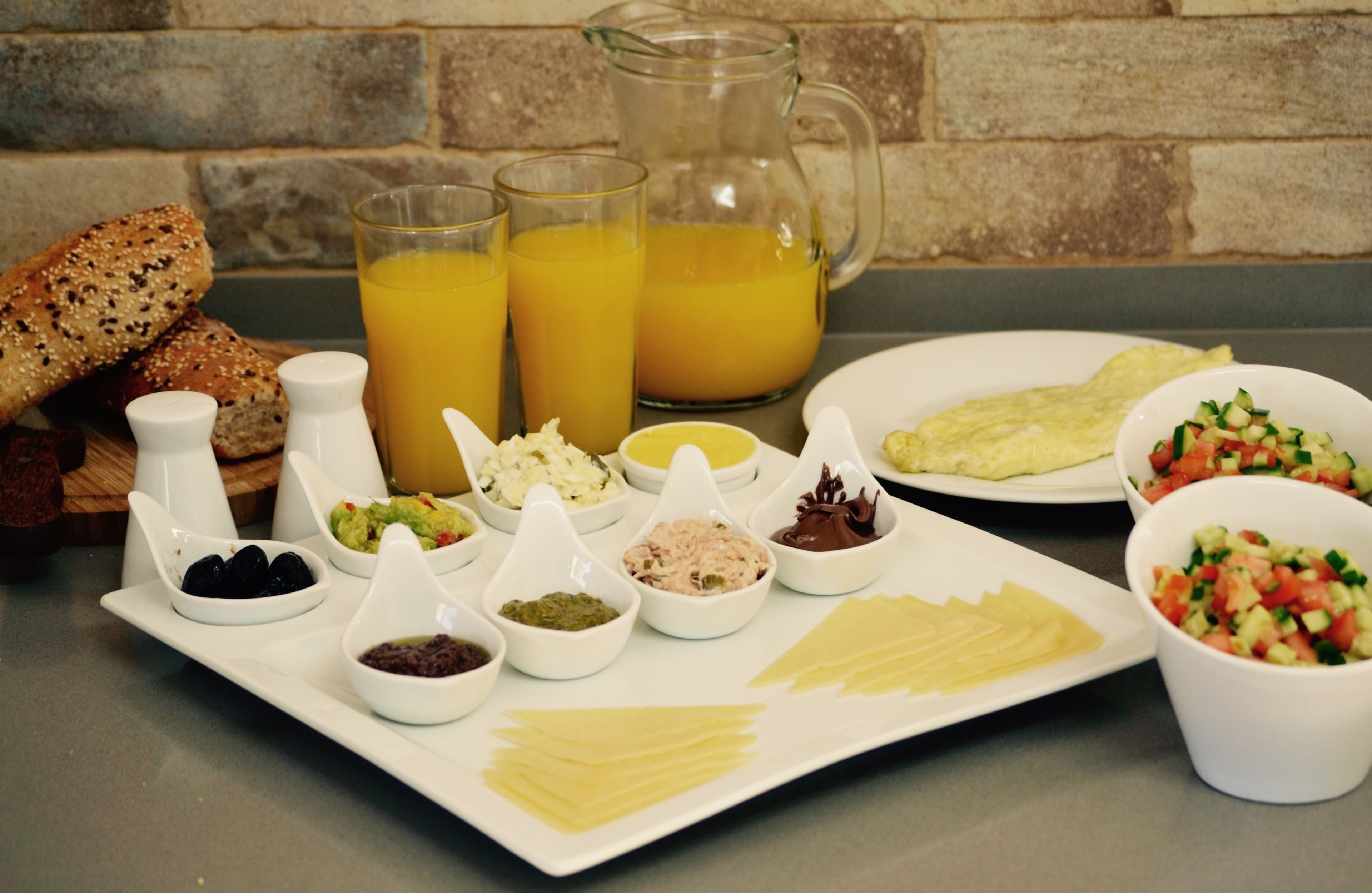 A breakfast table with various food items, including bread, eggs, and a pitcher of orange juice.