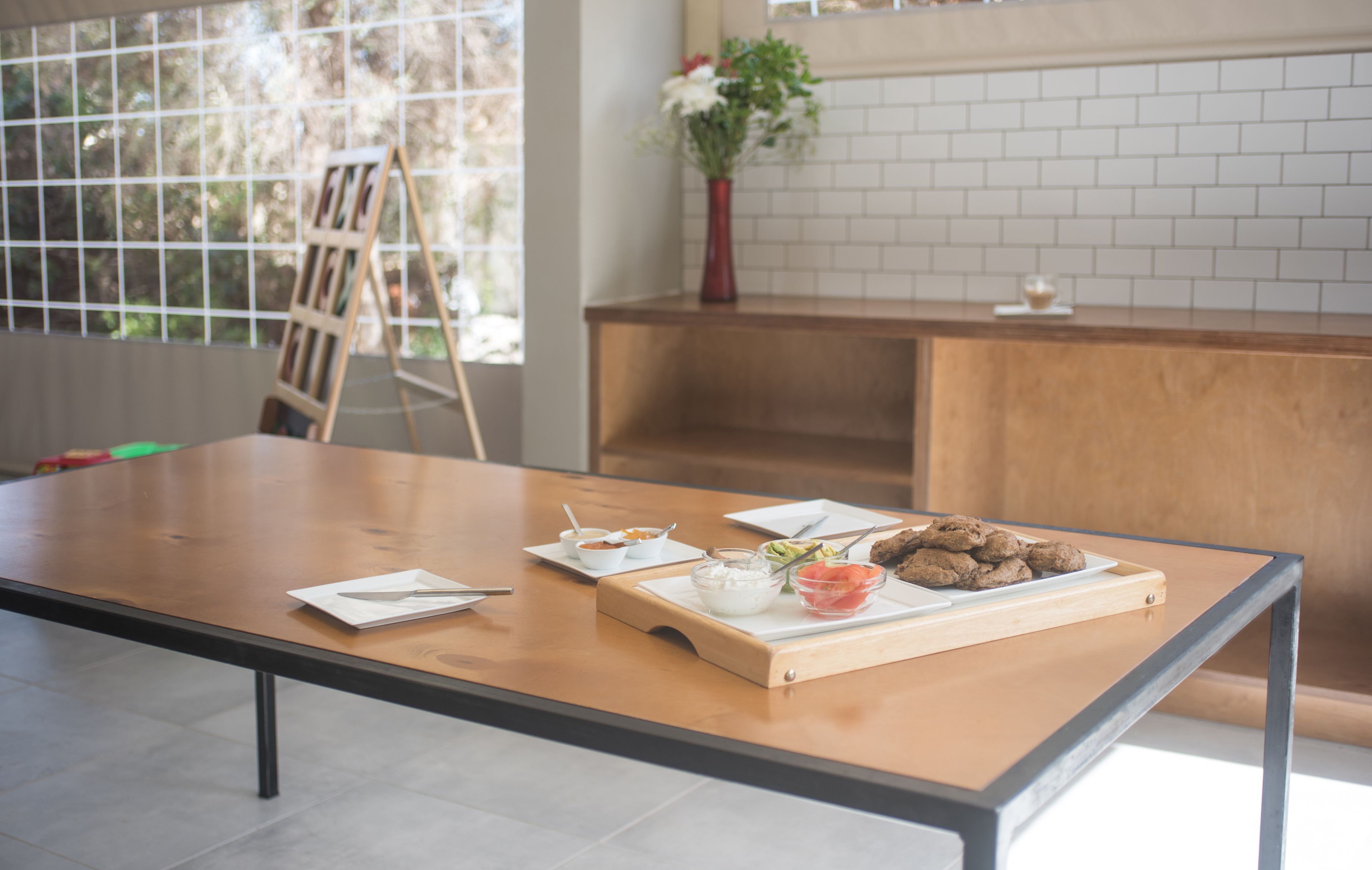 Una cocina moderna con una mesa de madera, un florero con flores y una bandeja de galletas.
