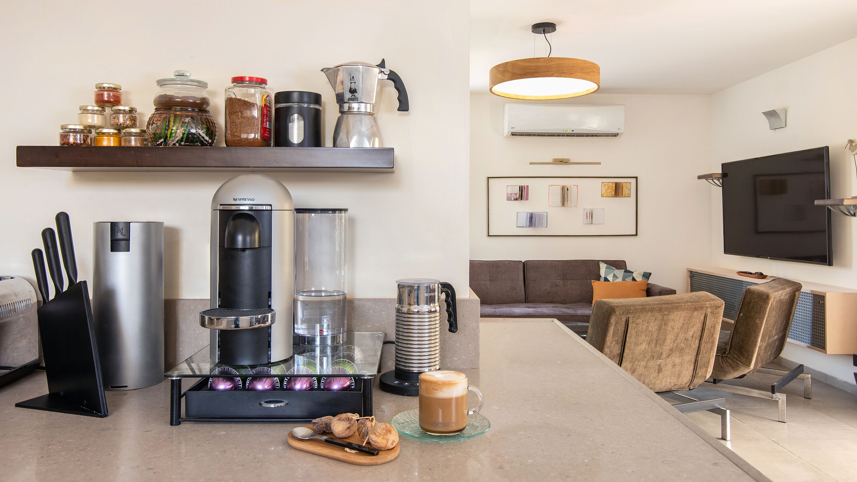 Een moderne keuken met een koffieapparaat, een kopje koffie en diverse keukengerei.